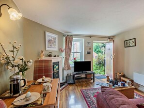 A cozy living room with a fireplace, a television, and a dining area with a coffee table and chairs. - 1 Bed in Cromer (oc-60268) (Northrepps)