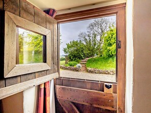 A wooden-framed window with a view of a garden and a stone pathway.