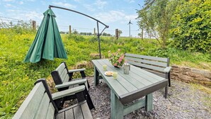 Ein Picknickbereich mit Tisch, Bänken und einem grünen, hängenden Baldachin.