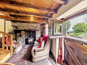 A cozy room with a stone fireplace, a sofa, and a view through a window. - 2 Bed in Craven Arms (oc-95107) (Kerry)