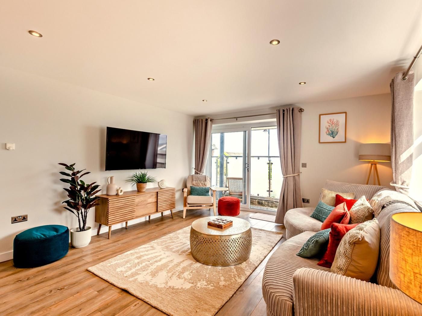 A modern living room with a sofa, a coffee table, a TV, and a balcony with a view.