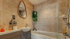 Een badkamer met een vrijstaand bad, een wastafelmeubel met een wastafel, een spiegel en een toilet.