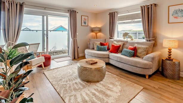 Een woonkamer met een bank, een ronde salontafel en uitzicht op zee door grote ramen.