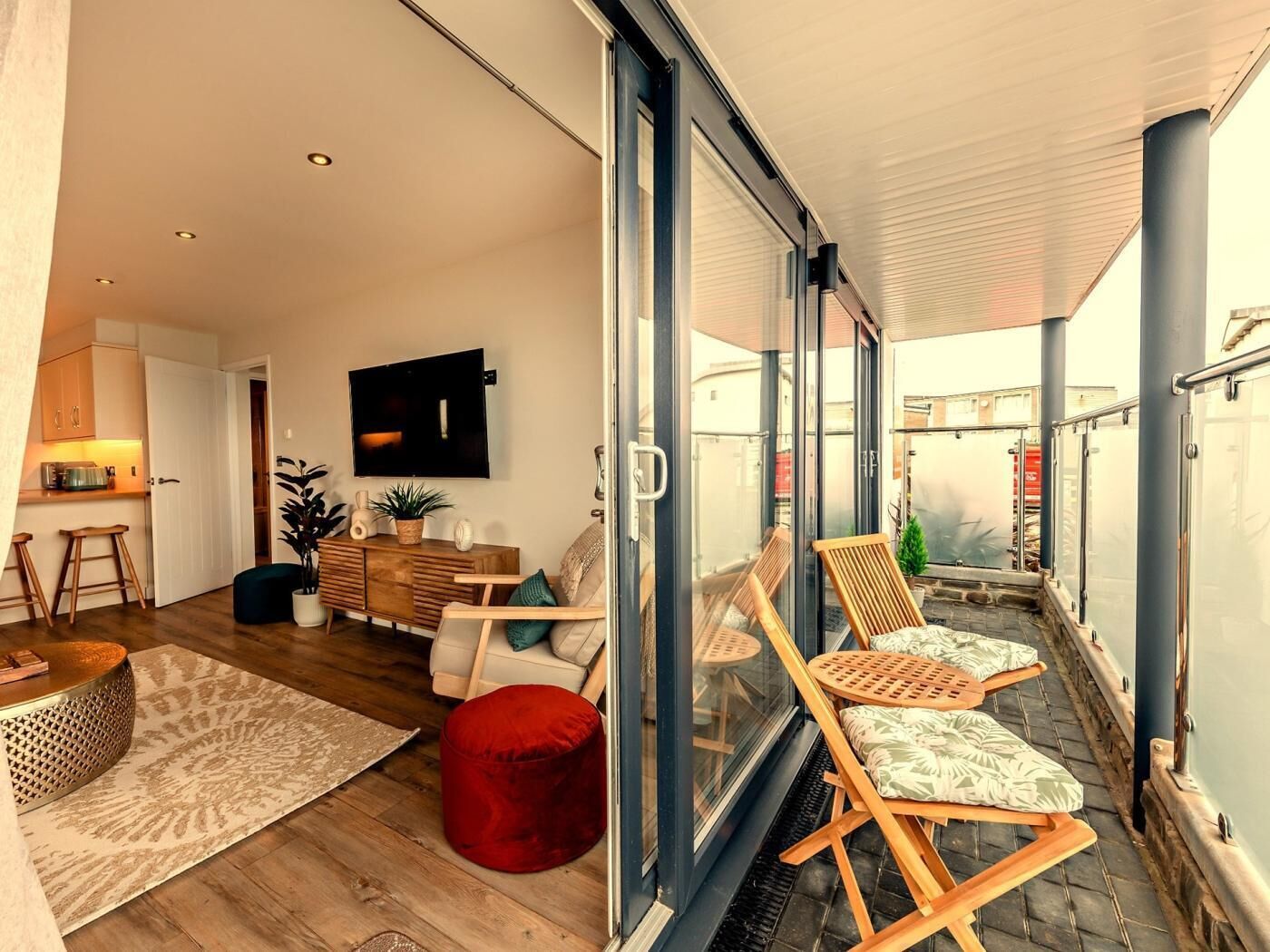 Un appartamento moderno con un balcone, un angolo cottura e un soggiorno con televisore.