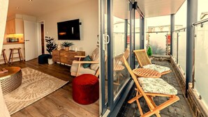 Een modern appartement met balkon, keuken en woonkamer met televisie.