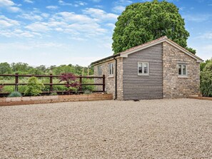 A stone building with a gravel driveway and a wooden fence. - 1 Bed in Shepton Mallet (oc-94296) (Pilton)