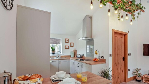 Eine moderne Küche mit weißen Schränken, einer Holz Arbeitsplatte und einer Frühstücksvorrichtung mit Croissants, Kaffee und Orangensaft.