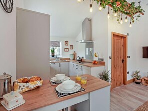 Eine moderne Küche mit weißen Schränken, einer Holz Arbeitsplatte und einer Frühstücksvorrichtung mit Croissants, Kaffee und Orangensaft.