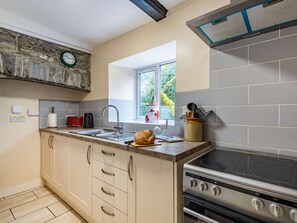 Una cocina con horno empotrado, un lavamanos y un ventanal que proporciona luz natural.