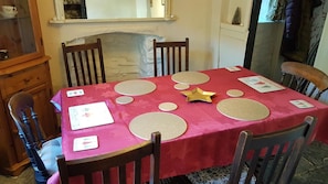 Una mesa de comedor con mantel rojo, rodeada de sillas de madera y decorada con posavasos con forma de estrella y círculo.