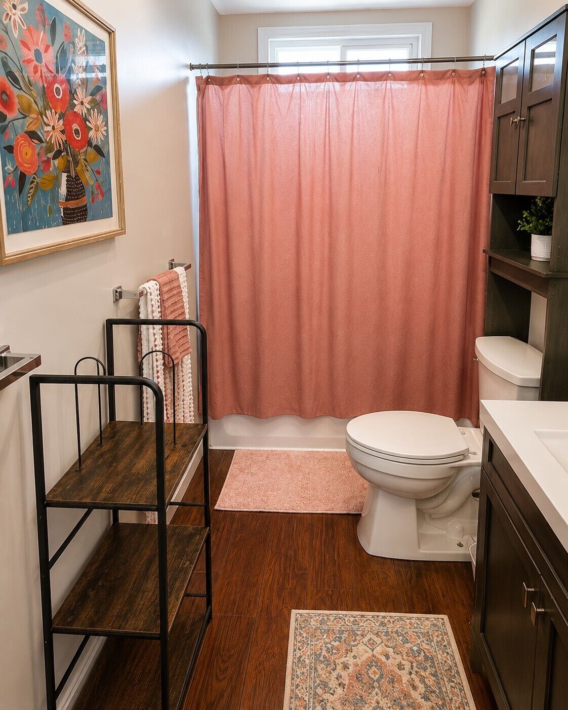 Une salle de bain avec un rideau de douche, des toilettes, un lavabo et une étagère sur laquelle est posée une plante.