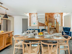 A dining area with a wooden table set for four, surrounded by wicker chairs. - 3 Bed in Carlisle (oc-95095) (Arthuret)