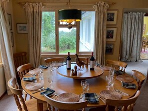 A round dining table with chairs, a chandelier, and wine bottles. - 5 Bed in Lochailort (oc-ca231) (Glenuig)