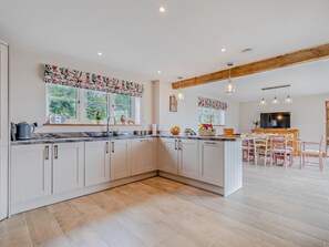 A modern kitchen with white cabinets, a marble countertop, and a wooden ceiling beam. - 4 Bed in Stoke-on-trent (oc-95163) (Longsdon)