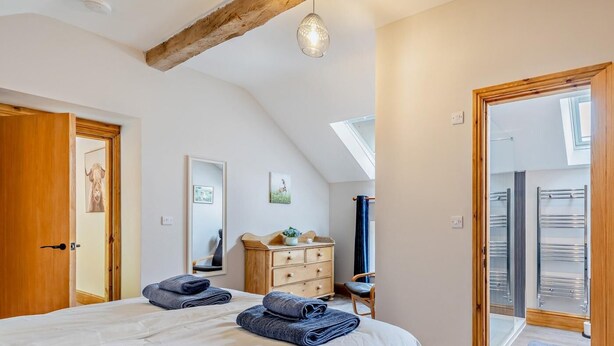 Une chambre à coucher comprenant un lit, une commode, un miroir et une porte donnant sur un balcon.