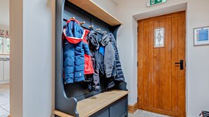 Un couloir avec un meuble pour ranger les manteaux, une porte en bois et un panneau indiquant les consignes de sécurité incendie.