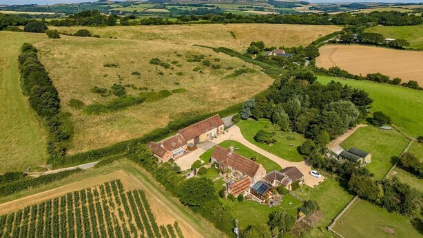 Luchtbeeld van een landgoed met een groot huis, omliggende velden en een klein vijvertje.