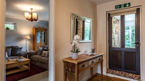 Een gezellige woonkamer met een bank, een houten salontafel, een lamp, een spiegel en een bureau met een bloevas.