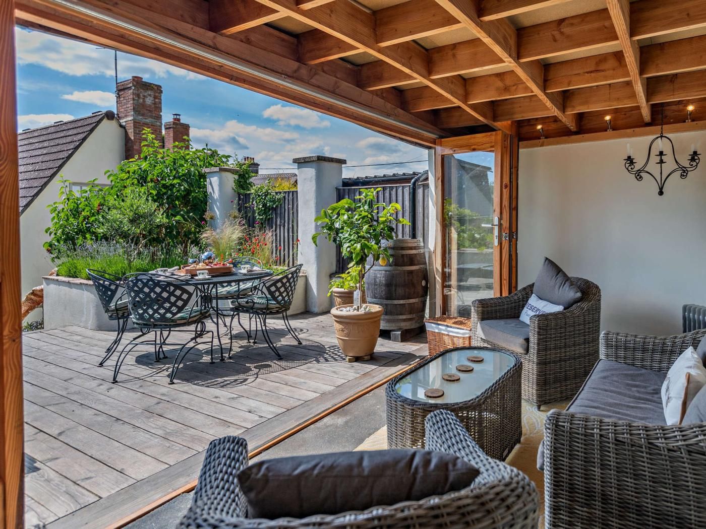 An outdoor patio with wicker furniture, a round table, and potted plants.