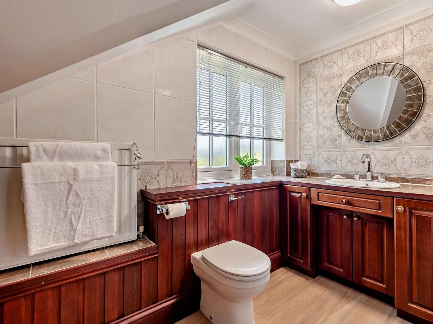 A bathroom with a toilet, sink, vanity, and a window with blinds.