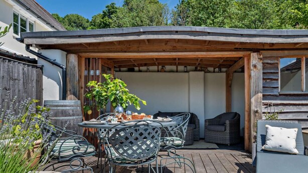 Un patio cubierto al aire libre con una mesa, sillas, un sofá y una planta en maceta.
