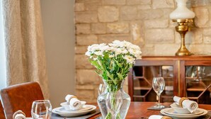 Una mesa de comedor dispuesta con platos, vasos y un jarrón de flores.