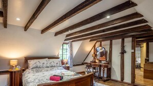 Una camera da letto con un letto in legno, una scrivania, una sedia e uno specchio.