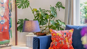 A blue sofa with a floral pillow, a patterned lamp, and a large green plant in a room with a framed picture on the wall. - 3 Bed in Yarmouth (oc-94802) (Cranmore)