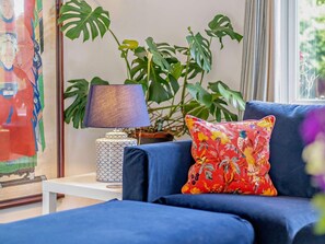 A blue sofa with a floral pillow, a patterned lamp, and a large green plant in a room with a framed picture on the wall. - 3 Bed in Yarmouth (oc-94802) (Cranmore)