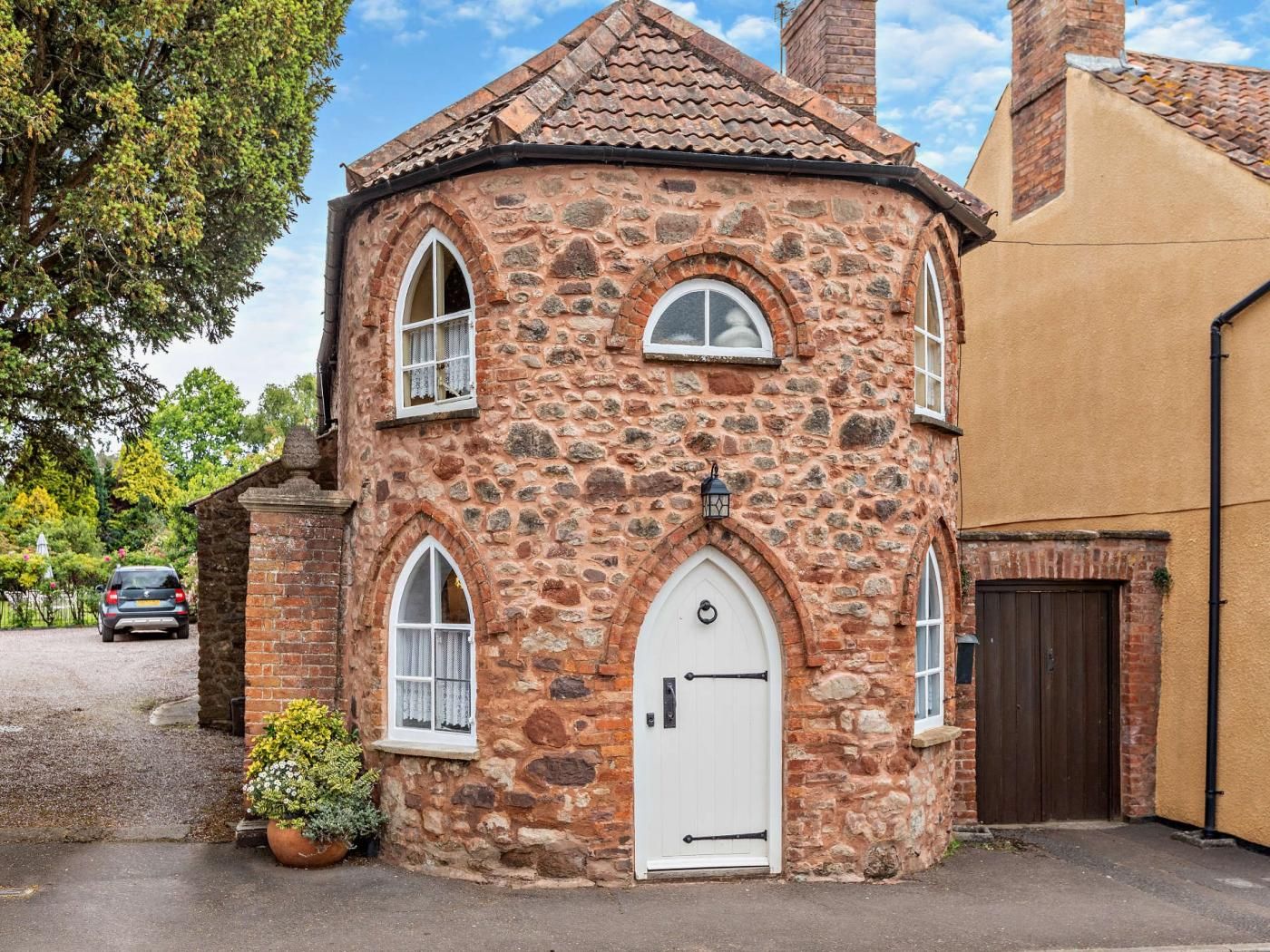 A stone building with a white door, arched windows, and a small garden area.