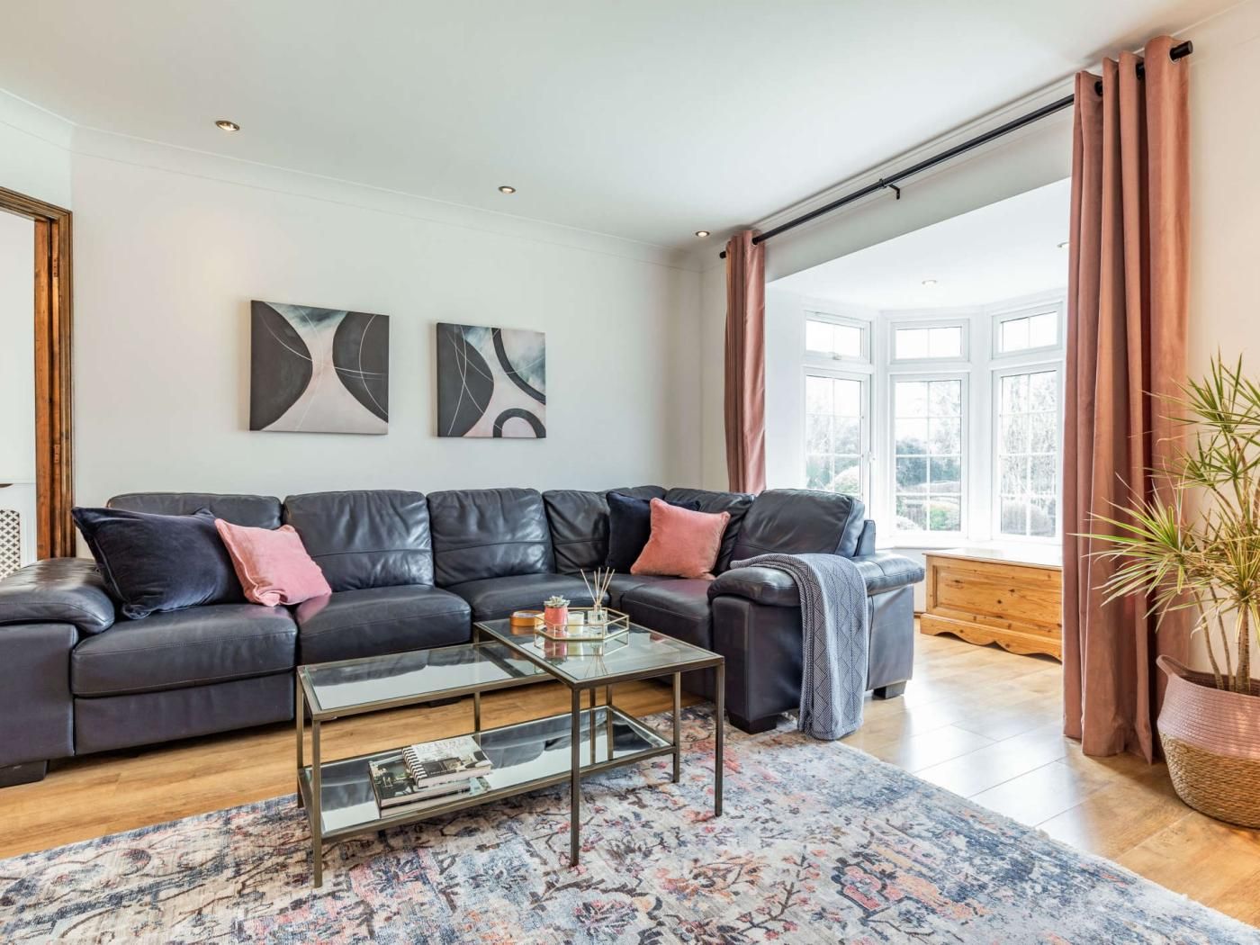 A modern living room with a leather sofa, a glass coffee table, and abstract wall art.