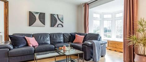 A modern living room with a leather sofa, a glass coffee table, and abstract wall art.
