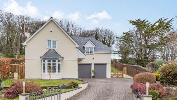 Ein zweistöckiges Haus mit Garage, gepflasterter Auffahrt und einem umzäunten Garten.