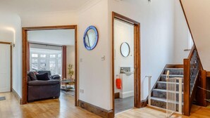 Ein geräumiger Wohnbereich mit Sofa, Couchtisch und Teppich. Eine Treppe mit Handlauf führt zu einer oberen Etage.