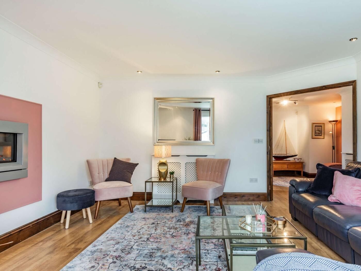 A living room with a fireplace, two chairs, a sofa, a coffee table, and a mirror.