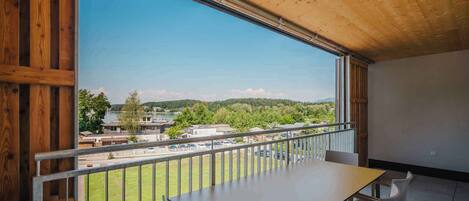 Un balcón con vista a una zona residencial, una mesa y sillas.
