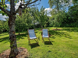 Two outdoor chairs on a grassy lawn with trees in the background. - 1 Bed in Ilfracombe (oc-95228) (Combe Martin)