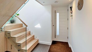 Eine moderne Treppe mit Glastrennwand, Holzvertäfelung und einer Tür mit kleinem Fenster.