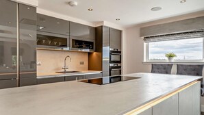 A modern kitchen with a large island, built-in appliances, and a window with a view. - 1 Bed in Glasgow (oc-83392) (Eaglesham)