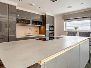 A modern kitchen with a large island, built-in appliances, and a window with a view. - 1 Bed in Glasgow (oc-83392) (Eaglesham)