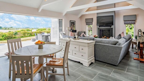 A modern living room with a dining area, a fireplace, and a view of the countryside. - 1 Bed in Glasgow (oc-83392) (Eaglesham)