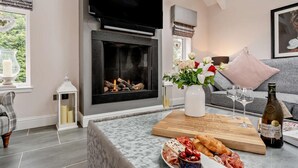 A living room with a fireplace, a sofa, a coffee table with food and drinks, and a TV mounted above the fireplace. - 1 Bed in Glasgow (oc-83392) (Eaglesham)