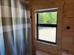 A wooden cabin interior with a window, a curtain, and a bench. - Cozy 1-bedroom log cabin in peaceful Gouldsboro with AC & view of Frenchman Bay (Gouldsboro)