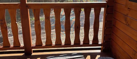 A wooden deck with a bench and a table, overlooking a forested area.