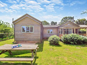 A wooden cabin with a picnic table and a small garden area.