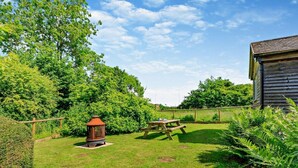 A well-maintained grassy yard with a wooden picnic table and a lantern. - 3 Bed in Watchet (oc-95161) (Washford)