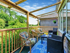 A wooden deck with wicker furniture, a table, and chairs.