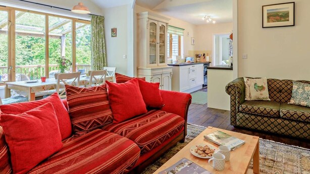 A cozy living room with a sofa, a dining table, and a kitchen area. - 3 Bed in Watchet (oc-95161) (Washford)