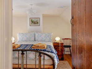 A bedroom with a bed, a bedside lamp, a wooden nightstand, a chair, and a door. - 1 Bed in Bristol (oc-95178) (Blagdon)