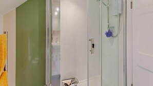 Una doccia vetrata con soffione a mano e spazzola da bagno.